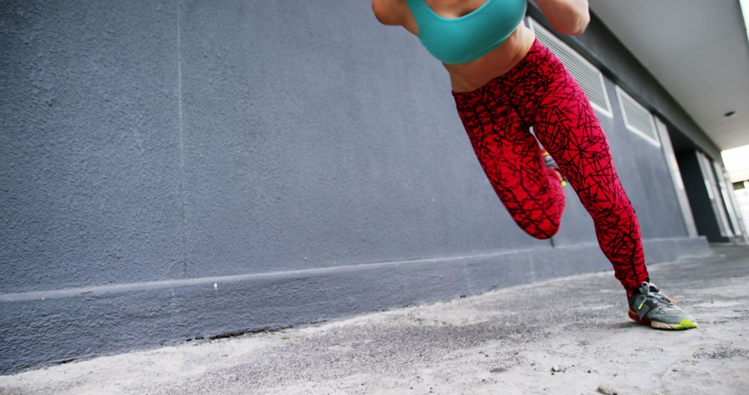 Female Athlete Running by Urban Building Wall in Bright Sportswear - Free Images, Stock Photos and Pictures on Pikwizard.com