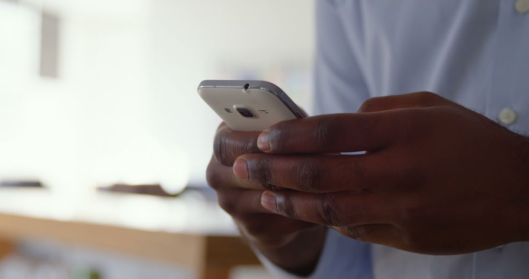 Close-Up of Businessman Texting on Smartphone in Modern Office