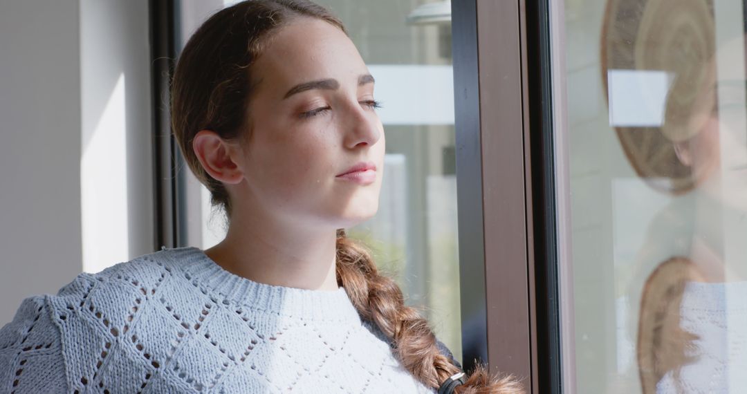 Young Woman Relaxing by Window with Eyes Closed - Free Images, Stock Photos and Pictures on Pikwizard.com