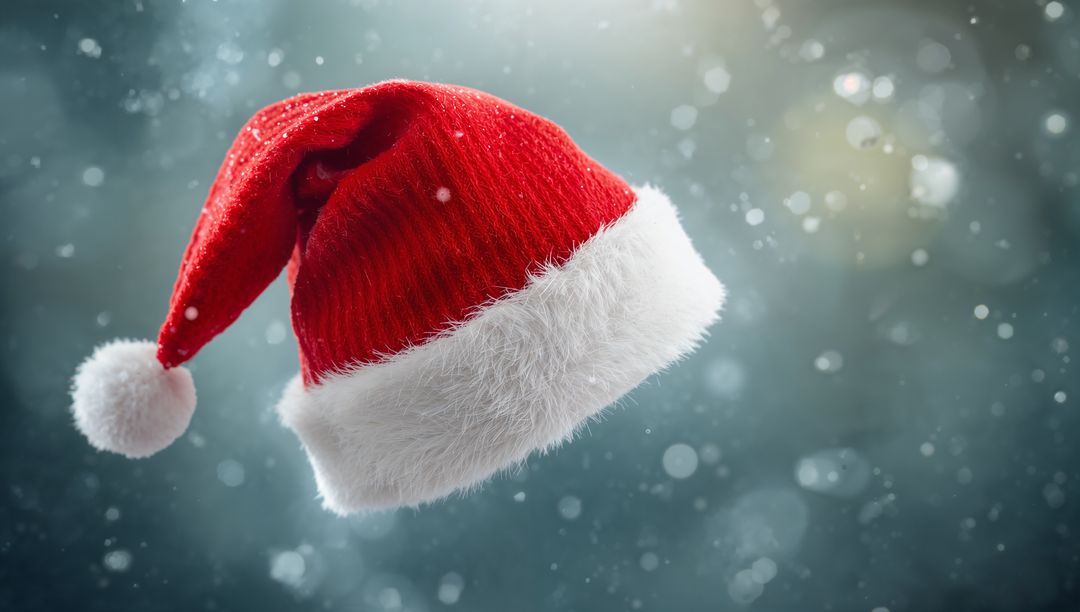 Floating red Santa hat glowing in snowy bokeh, knit texture and fluffy white pompom