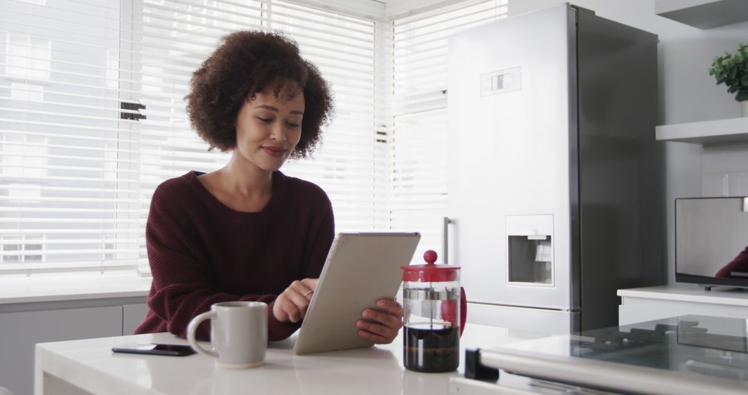 Woman Using Tablet in Modern Kitchen with Coffee - Free Images, Stock Photos and Pictures on Pikwizard.com