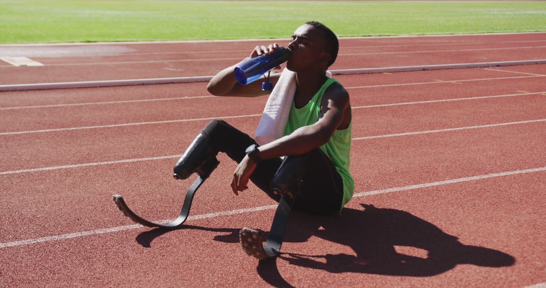 Disabled Athlete Resting by Track with Prosthetic Legs