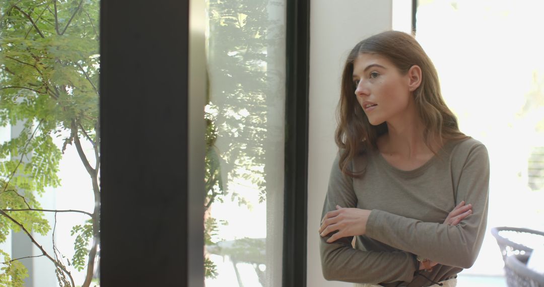 Woman Gazing Through Window in Modern Minimalist Room with Tree View