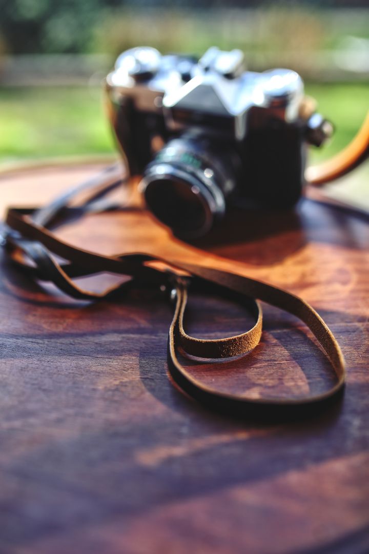 Vintage Camera with Leather Strap on Wooden Table Blurred Background - Free Images, Stock Photos and Pictures on Pikwizard.com