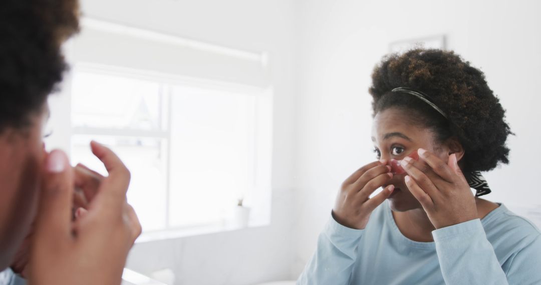 African American Woman Applying Skincare Product with Red Bandage in Bathroom - Free Images, Stock Photos and Pictures on Pikwizard.com