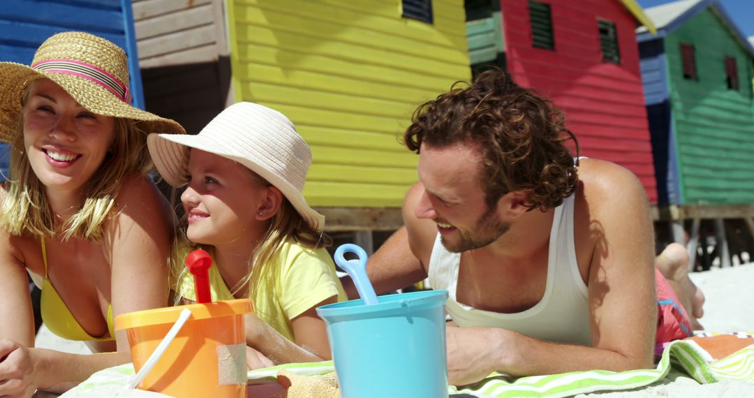 Caucasian Family Bonding on Sunny Beach with Colorful Cabins - Free Images, Stock Photos and Pictures on Pikwizard.com