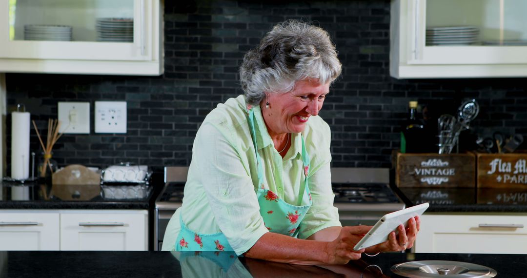 Smiling senior woman using tablet in modern kitchen - Free Images, Stock Photos and Pictures on Pikwizard.com