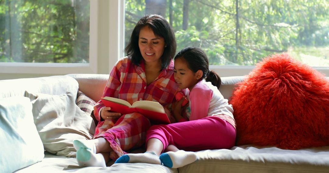 Mother and Daughter Reading Book on Couch in Sunlit Room - Free Images, Stock Photos and Pictures on Pikwizard.com