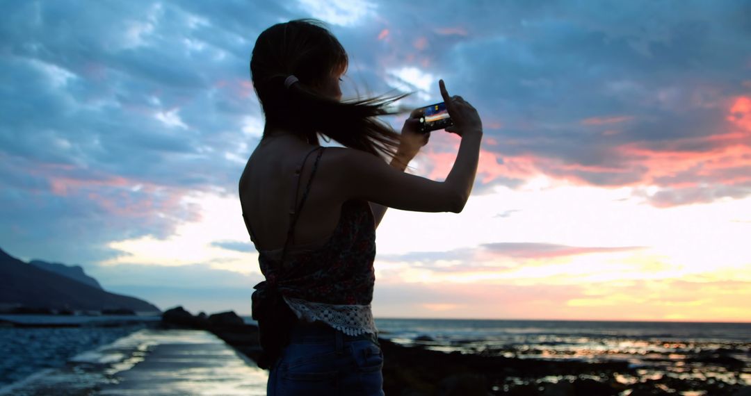 Woman capturing sunset by the sea with smartphone - Free Images, Stock Photos and Pictures on Pikwizard.com