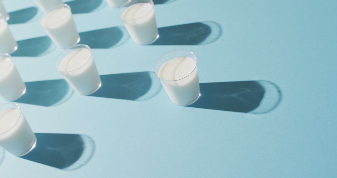 Image of row of glasses of milk on blue background - Free Images, Stock Photos and Pictures on Pikwizard.com