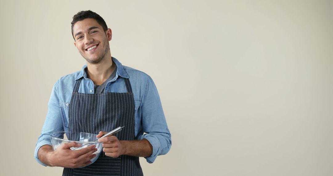 Smiling Young Man in Apron Mixing Ingredients in Kitchen - Free Images, Stock Photos and Pictures on Pikwizard.com