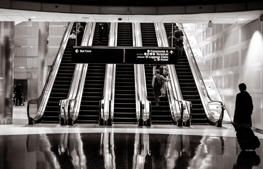 Passengers Using Airport Escalators in Black and White