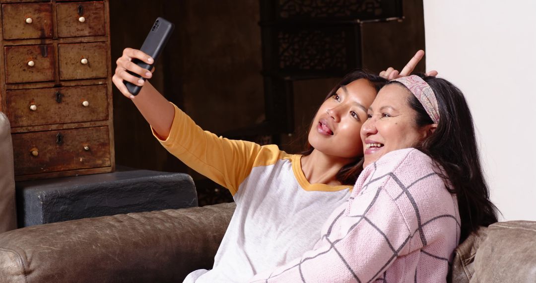 Mother and Daughter Smiling as They Take a Selfie at Home