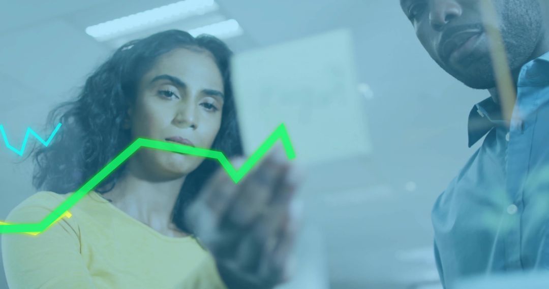 Two professionals analyzing green line graph on glass for teamwork and strategic planning