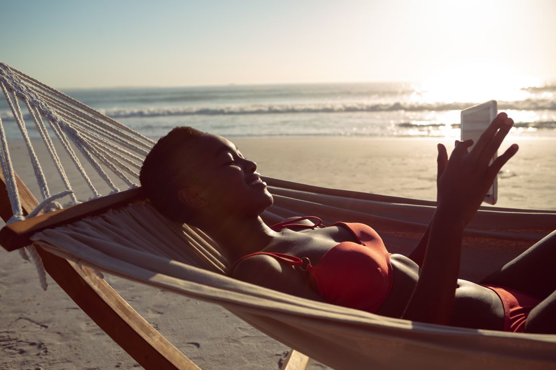 African-American Woman Relaxing in Hammock on Beach Using Tablet - Free Images, Stock Photos and Pictures on Pikwizard.com
