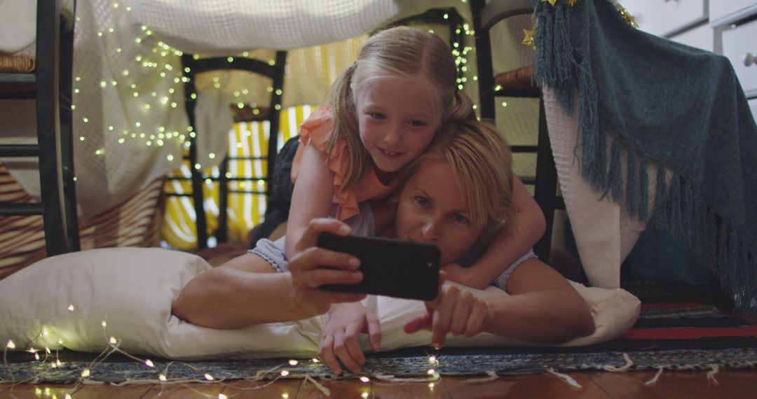 Mother and Daughter Enjoying Time in Pillow Fort with Fairy Lights Taking Selfies - Free Images, Stock Photos and Pictures on Pikwizard.com