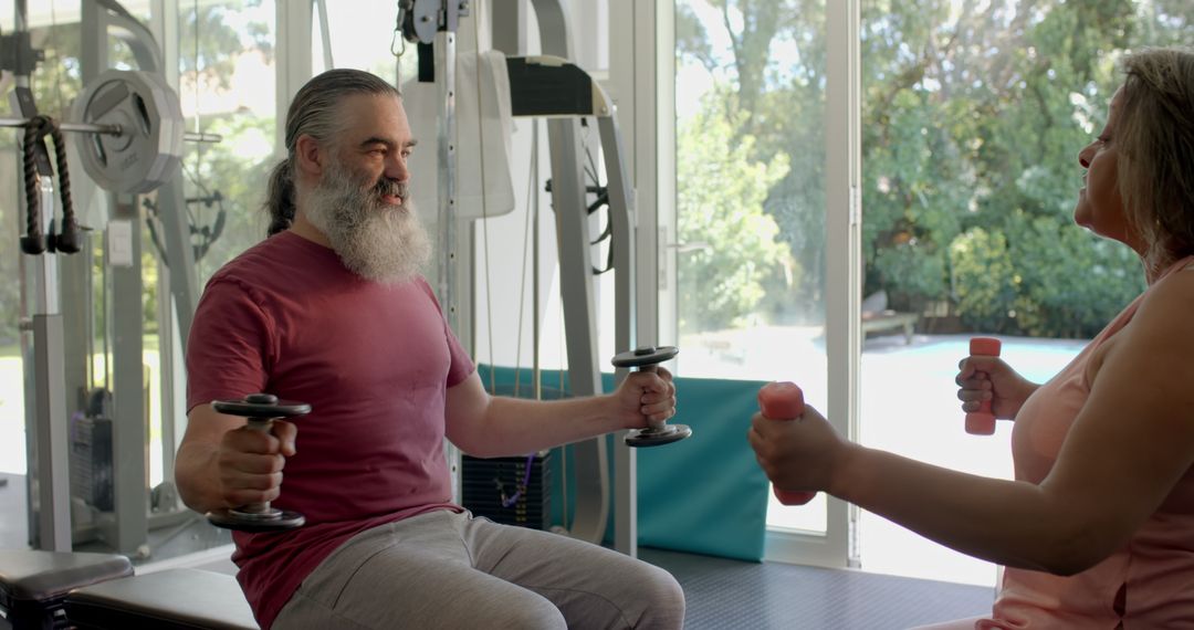 Senior Couple Exercising Together with Dumbbells in Gym