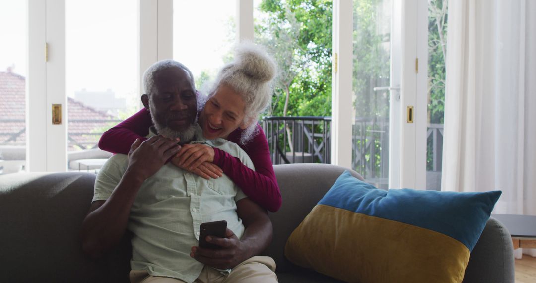 Joyful Senior Couple Relaxing on Couch Using Smartphone at Home - Free Images, Stock Photos and Pictures on Pikwizard.com