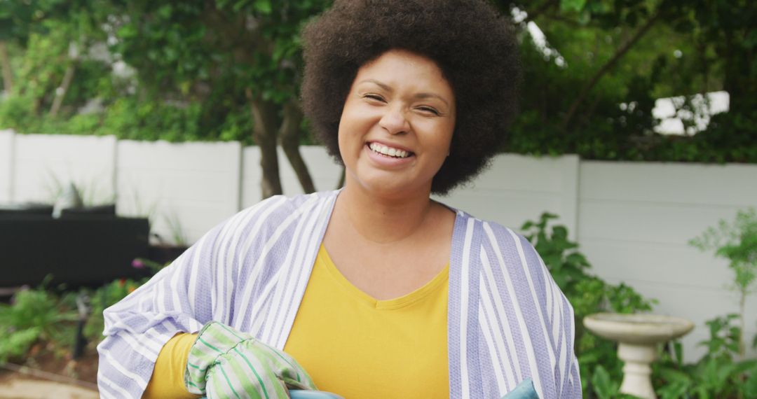 Image of happy plus size african american woman watering flowers in garden - Free Images, Stock Photos and Pictures on Pikwizard.com