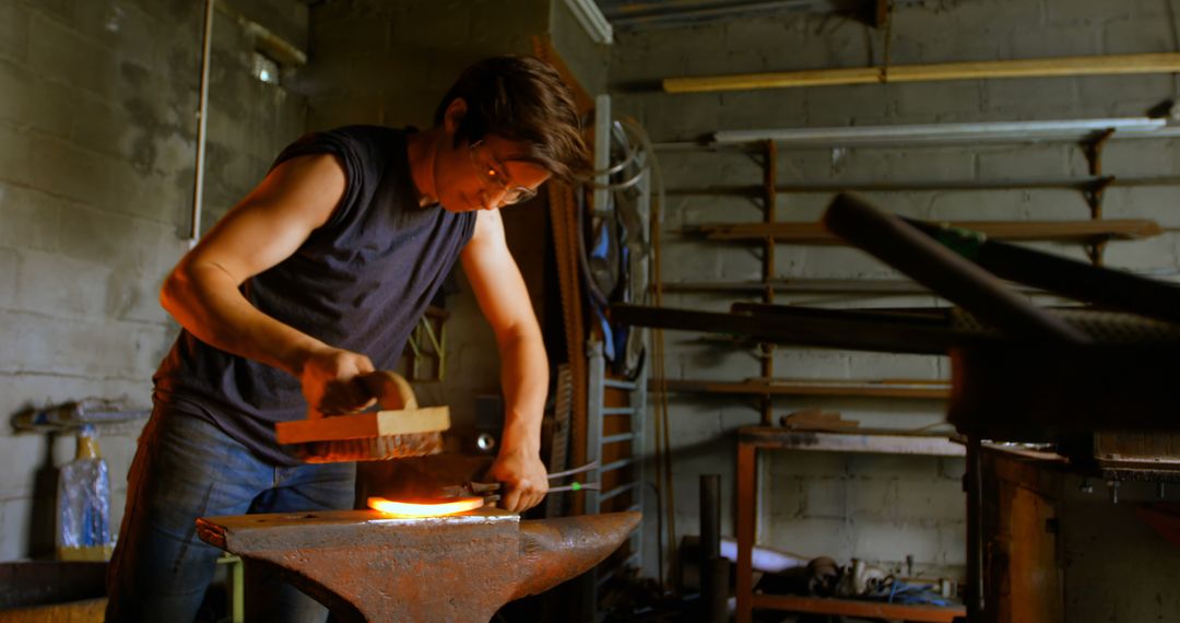 Male Blacksmith Forging Metal in Dimly Lit Workshop - Free Images, Stock Photos and Pictures on Pikwizard.com