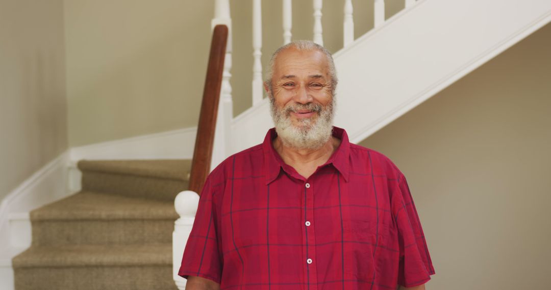 Smiling Elderly Man in Red Shirt Standing at Staircase - Free Images, Stock Photos and Pictures on Pikwizard.com