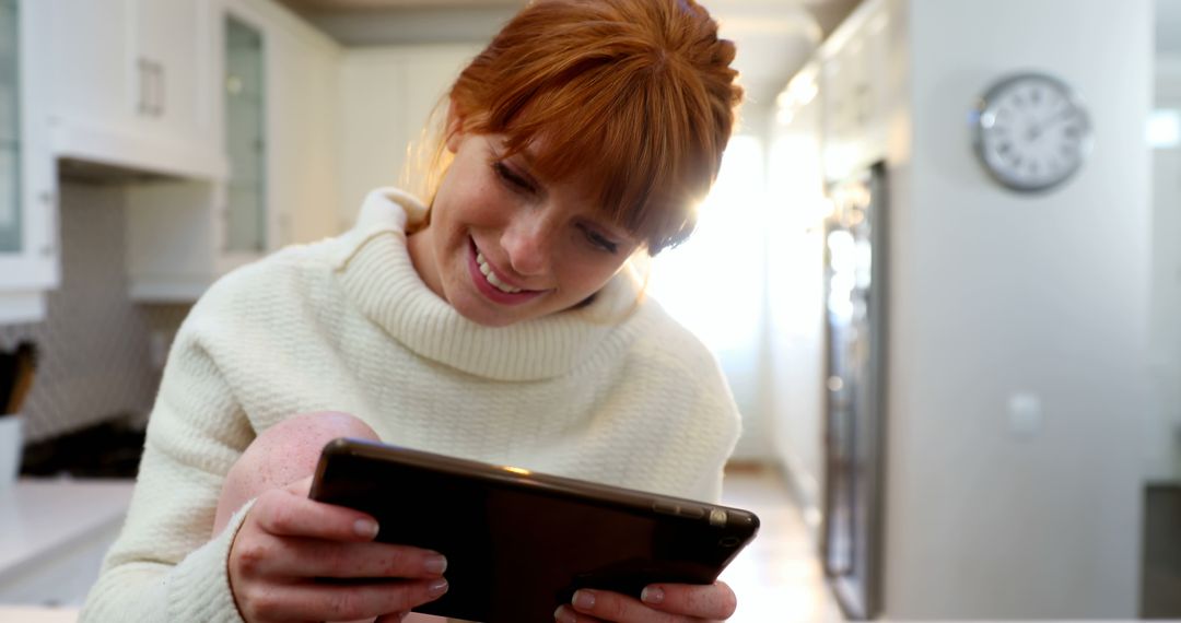 Smiling Woman Reading on Tablet in Modern Kitchen - Free Images, Stock Photos and Pictures on Pikwizard.com