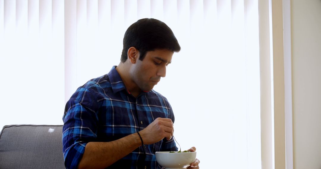 Young Man Eating Healthy Salad in Modern Living Room - Free Images, Stock Photos and Pictures on Pikwizard.com