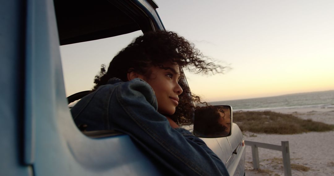 Young woman enjoying beach view from car window at sunset - Free Images, Stock Photos and Pictures on Pikwizard.com