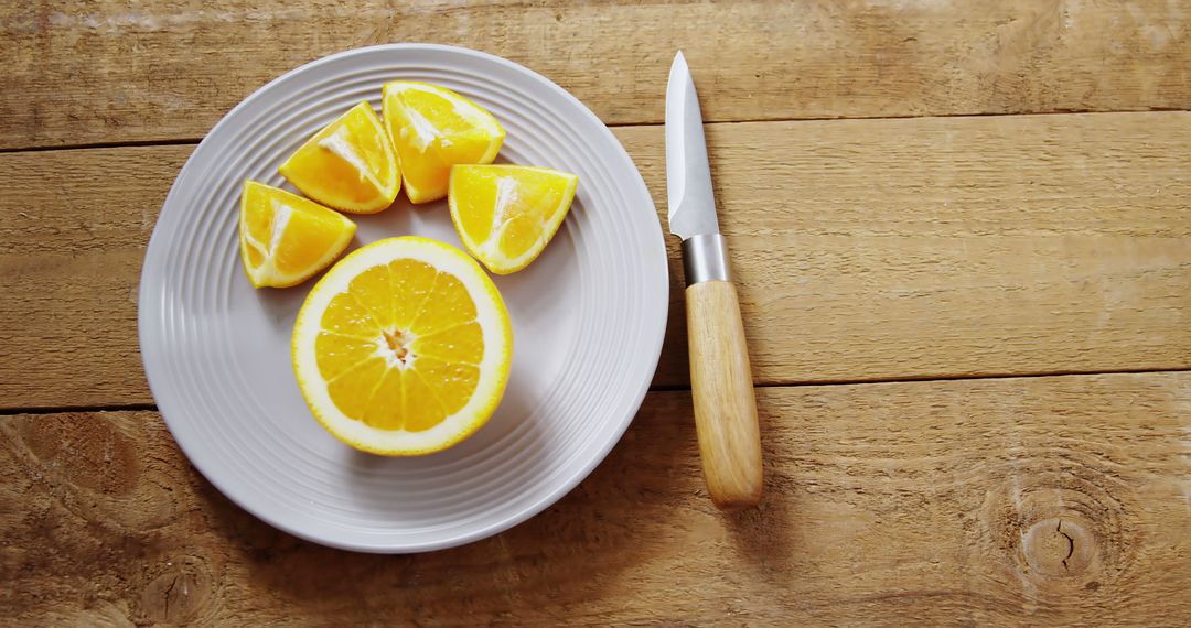 Sliced Oranges on White Plate with Wooden Knife on Rustic Table - Free Images, Stock Photos and Pictures on Pikwizard.com