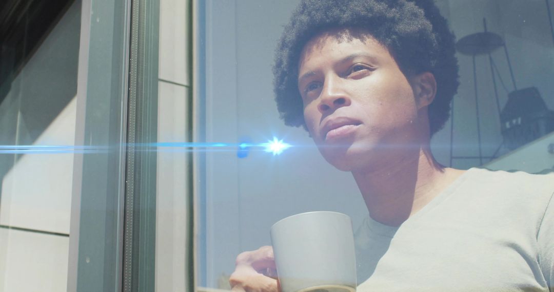 Man Relaxing at Window with Mug of Tea or Coffee