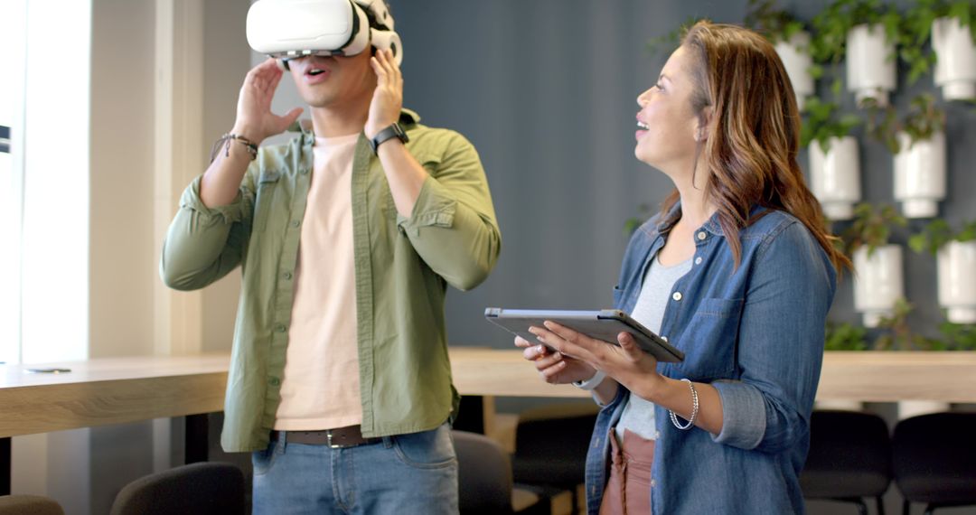 Diverse coworkers testing VR headset while colleague using tablet in modern office