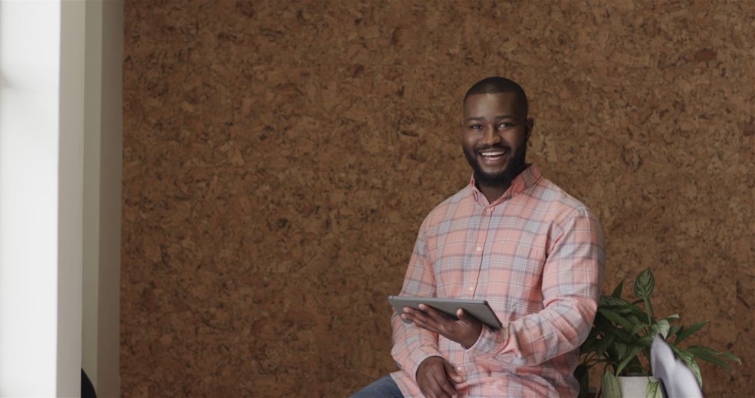 Smiling Man Holding Digital Tablet Against Cork Board Background - Free Images, Stock Photos and Pictures on Pikwizard.com