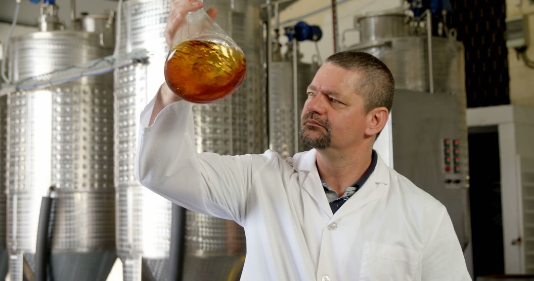 Scientist Examining Liquid in Laboratory Flask in Industrial Setting - Free Images, Stock Photos and Pictures on Pikwizard.com