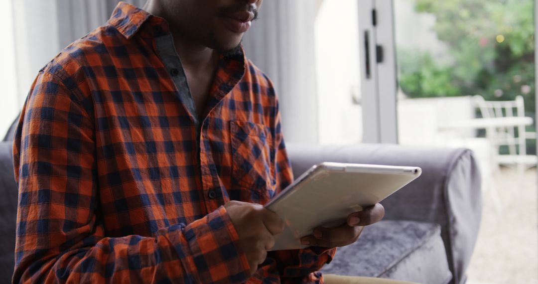 Man Using Tablet at Home in Casual Checkered Shirt - Free Images, Stock Photos and Pictures on Pikwizard.com