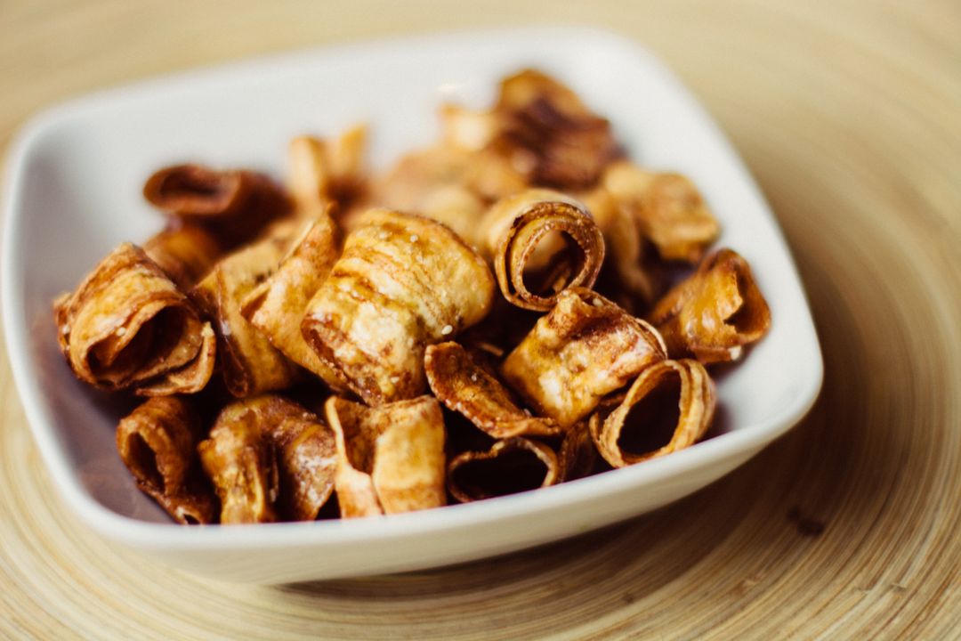 Crispy Rolled Snack Bites in White Ceramic Bowl on Wooden Surface Close-Up Texture