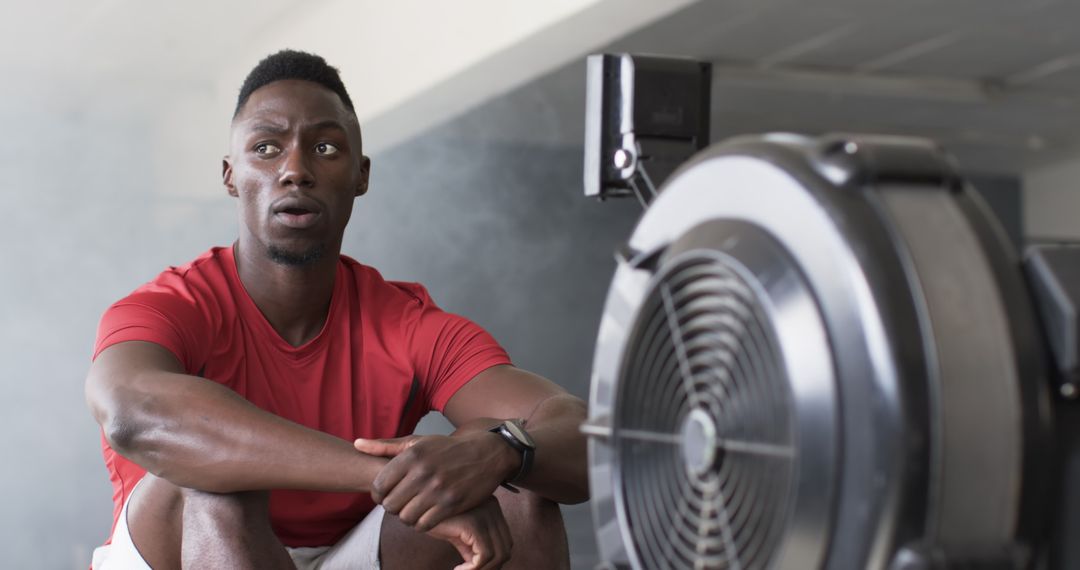 Athletic Man Resting by Rowing Machine in Modern Gym Environment