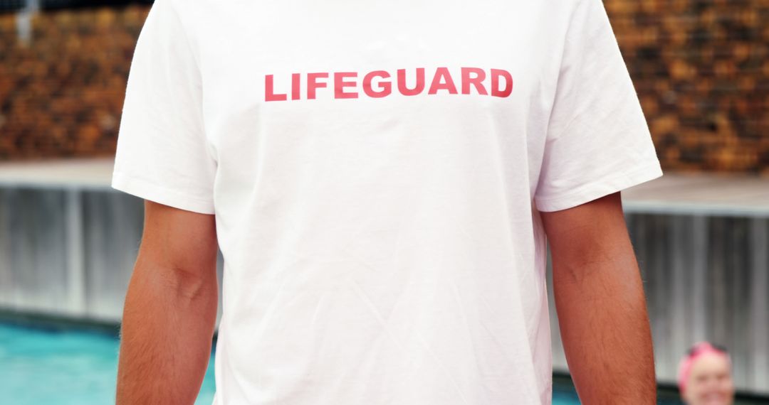 Lifeguard Wearing White Shirt with Red Text by Swimming Pool - Free Images, Stock Photos and Pictures on Pikwizard.com