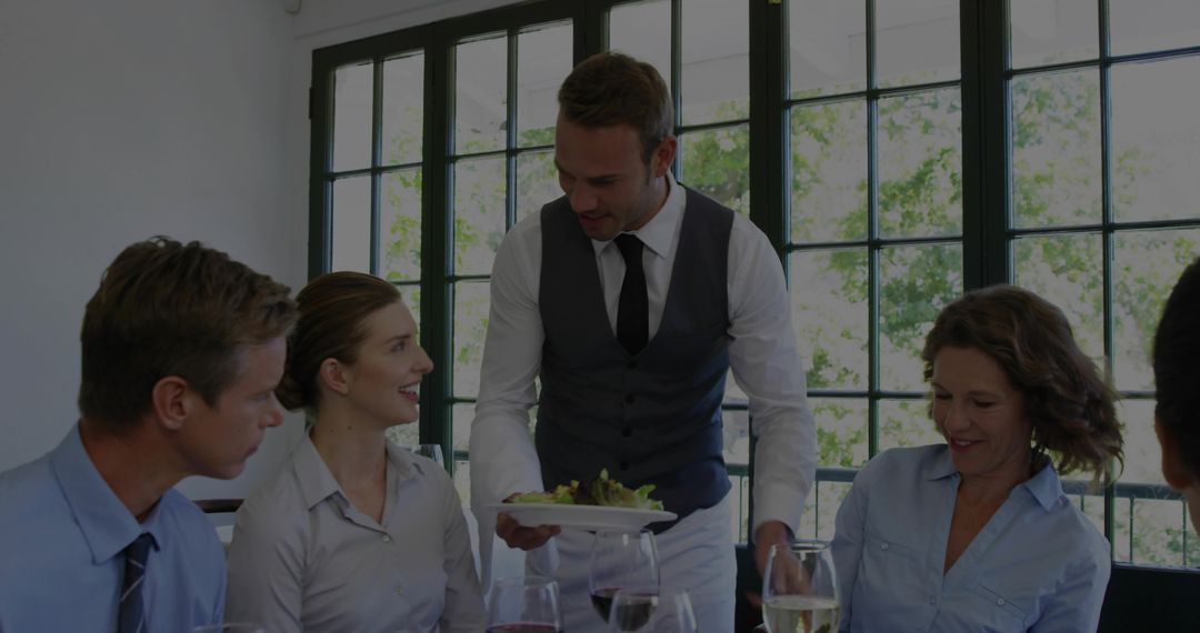 Server presenting plated salad to business lunch group in bright modern restaurant