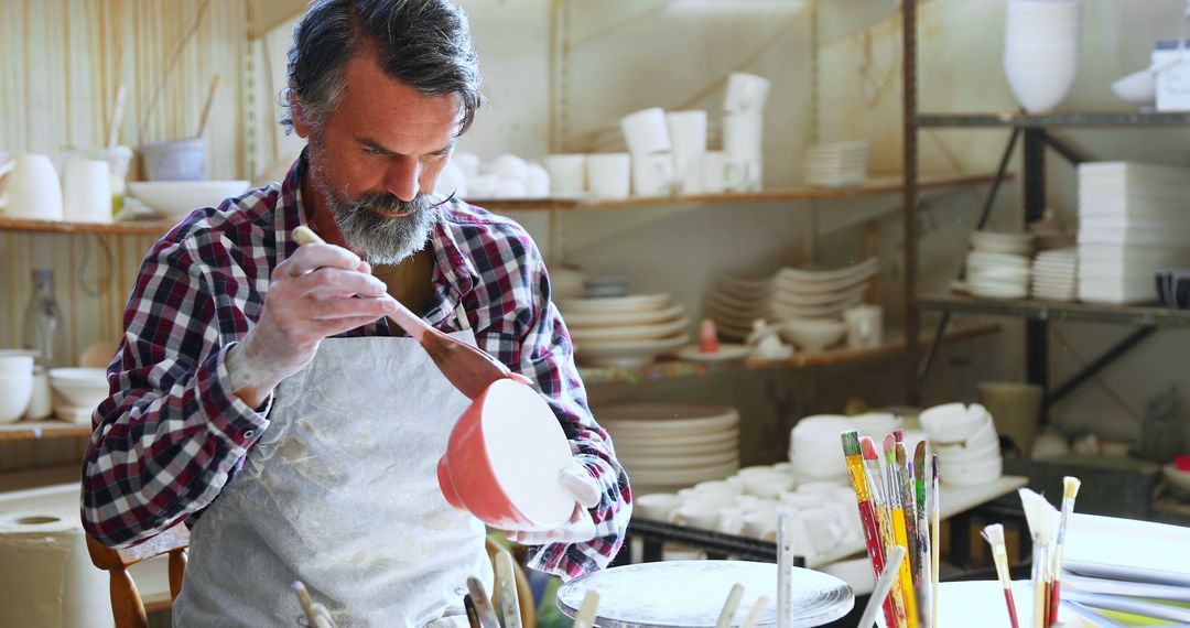 Middle-aged Male Potter Decorating Ceramic Pot in Workshop  - Free Images, Stock Photos and Pictures on Pikwizard.com