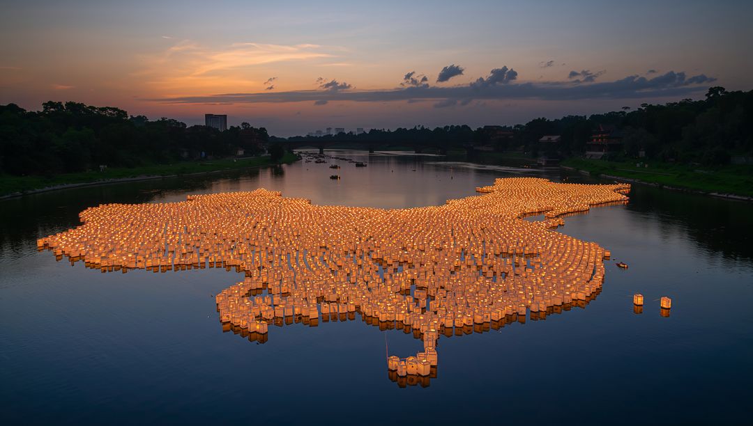 Lanterns Forming Map on Tranquil River Against Sunset