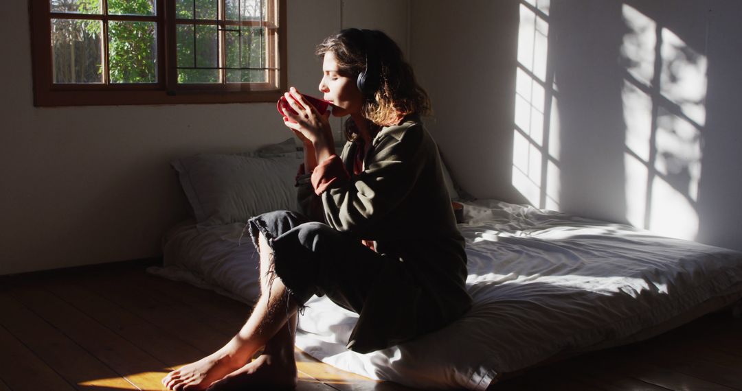 Woman Drinking Coffee by Bedroom Window in Morning Sunlight - Free Images, Stock Photos and Pictures on Pikwizard.com