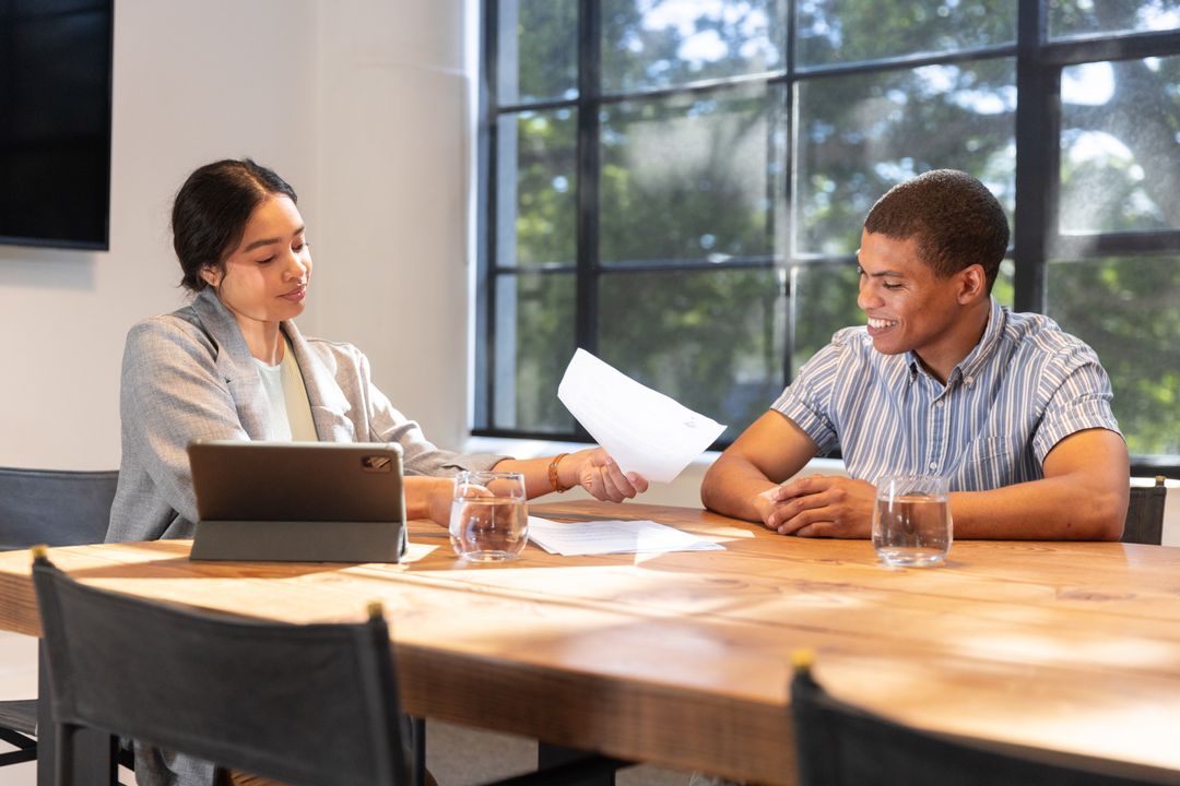 Colleagues Exchanging Documents in Bright Conference Room