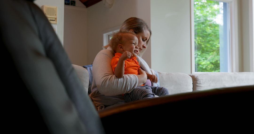 Mother Comforting Crying Baby in Bright Living Room - Free Images, Stock Photos and Pictures on Pikwizard.com