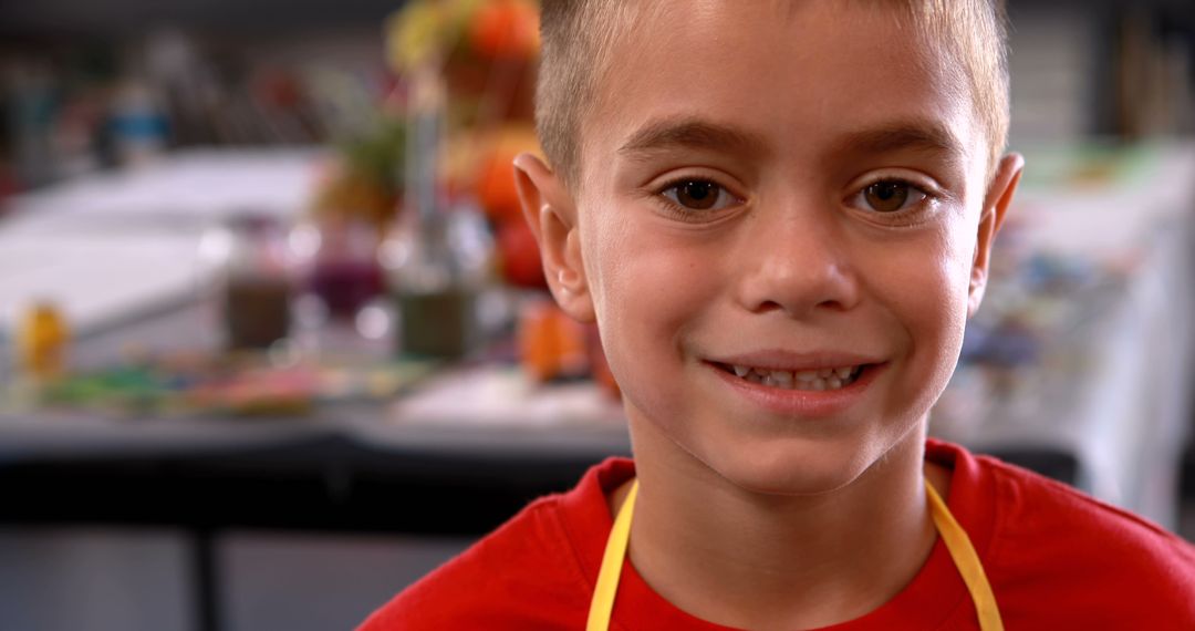 Smiling boy in art class wearing red shirt and apron - Free Images, Stock Photos and Pictures on Pikwizard.com