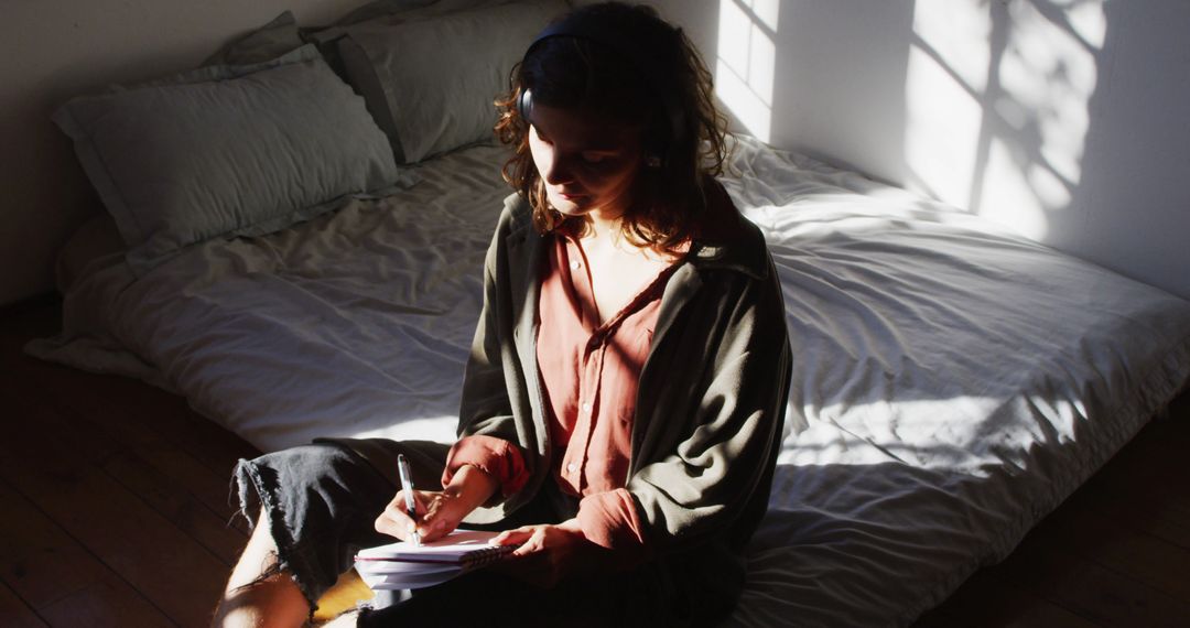 Young Woman Journaling on Bed in Sunlit Room, Capturing Quiet Moments - Free Images, Stock Photos and Pictures on Pikwizard.com