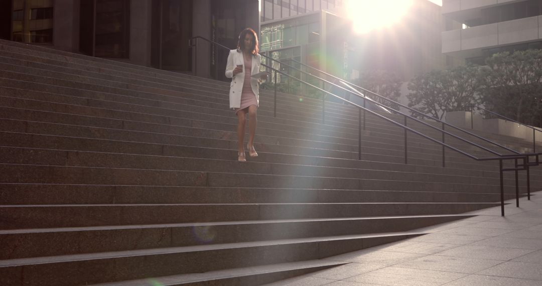 Businesswoman Walking Down Stairs in Urban Office Complex at Sunrise - Free Images, Stock Photos and Pictures on Pikwizard.com