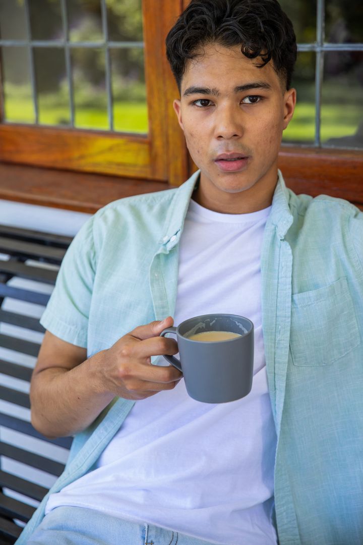 Young Man Enjoying Coffee on Porch with View of Garden