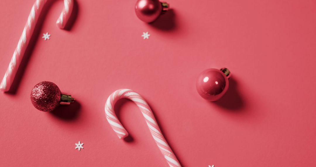 Festive Arrangement of Candy Canes and Christmas Ornaments on Red Background