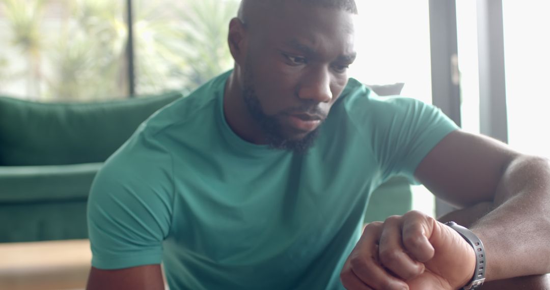 Man Relaxing Indoors Checking Smartwatch for Fitness Tracking