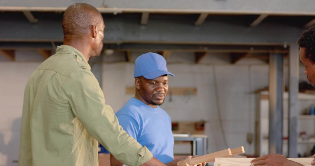 Carpenters examining wooden plank at workshop bench collaborating on custom furniture build